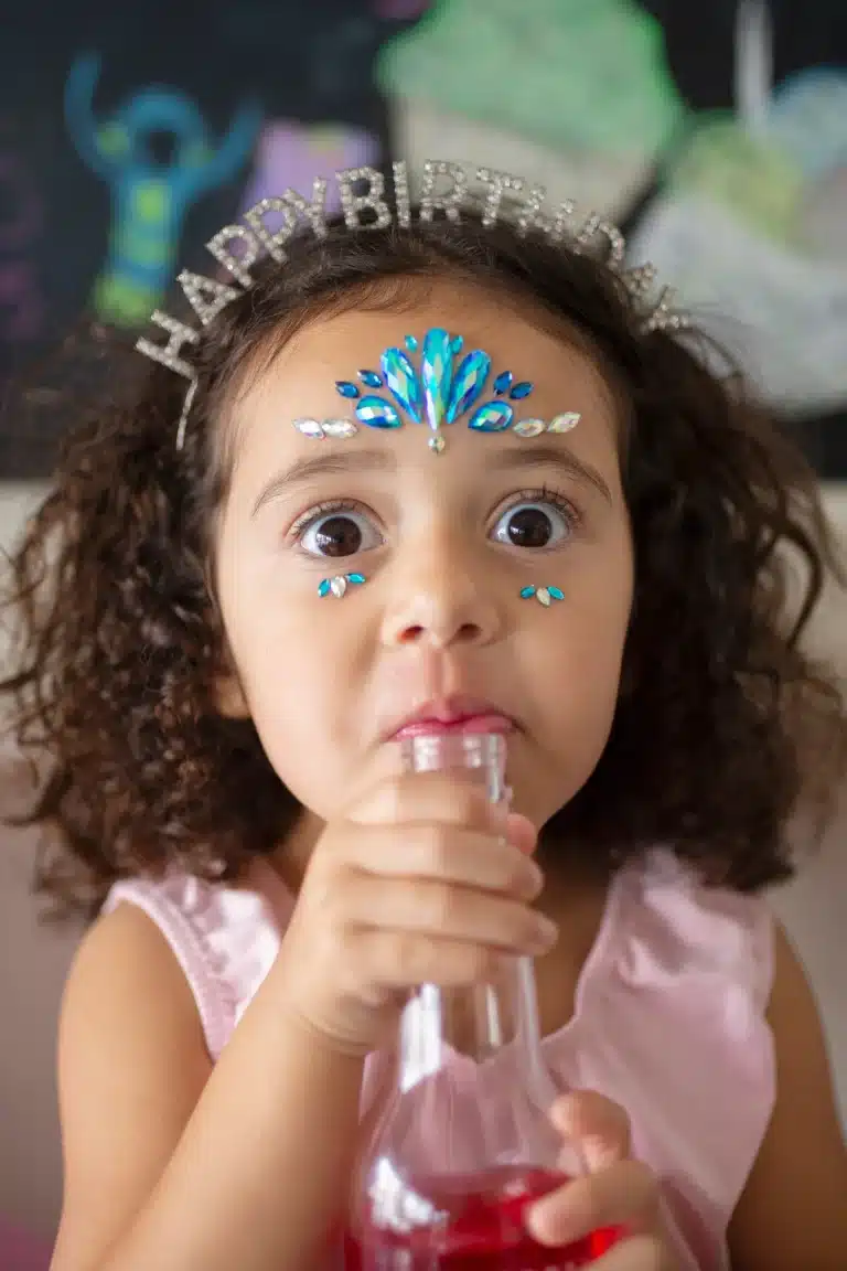 Meisje met Frozen gezicht stickers van blauwe en zilveren kristallen op haar voorhoofd en onder haar ogen