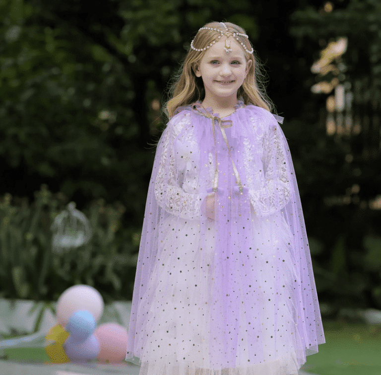 Meisje draagt een paarse cape, een prinsessencape van tule met goudkleurige sterren in de tuin