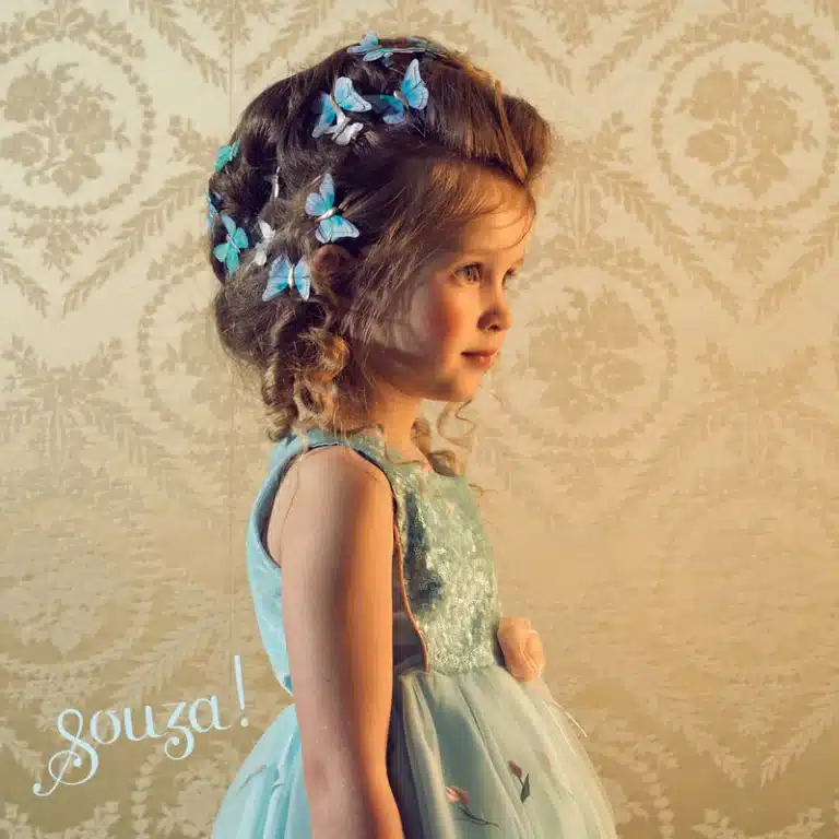 Blauwe meisjes feestjurk van Souza!, een prinsessenjurk met glinsterend lijfje en volle rok, gedragen door een meisje met vlinders in het haar