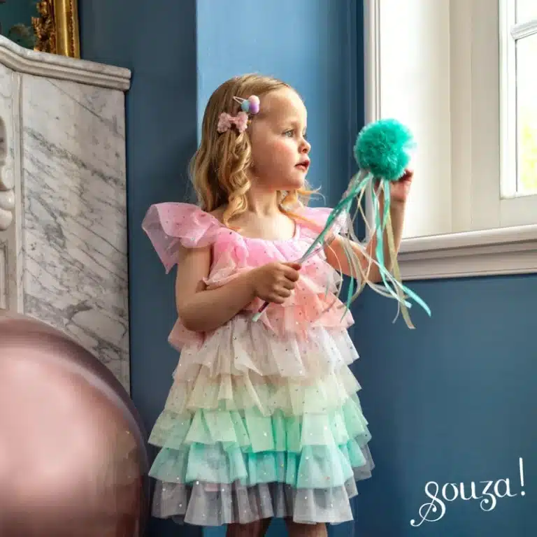 Meisje draagt de multicolor Fenne-prinsessenjurk met roze bovenkant en lagen tule, terwijl ze een versierde toverstaf vasthoudt