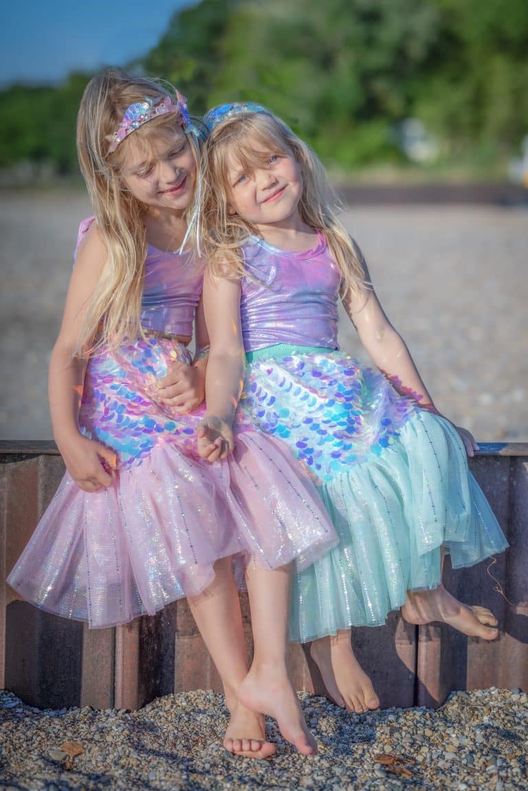 Twee meisjes dragen een roze zeemeermin rok met pailletten en tule; één meisje draagt ook de haarclip van Great Pretenders.